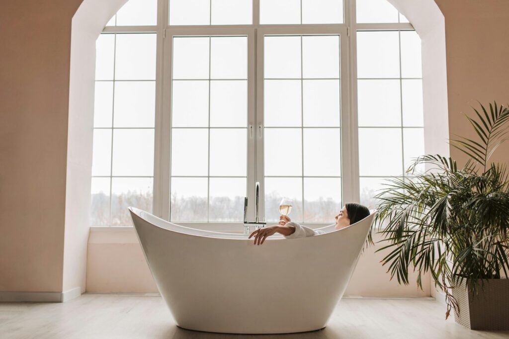 A serene scene of a woman enjoying a glass of wine while relaxing in a modern ba