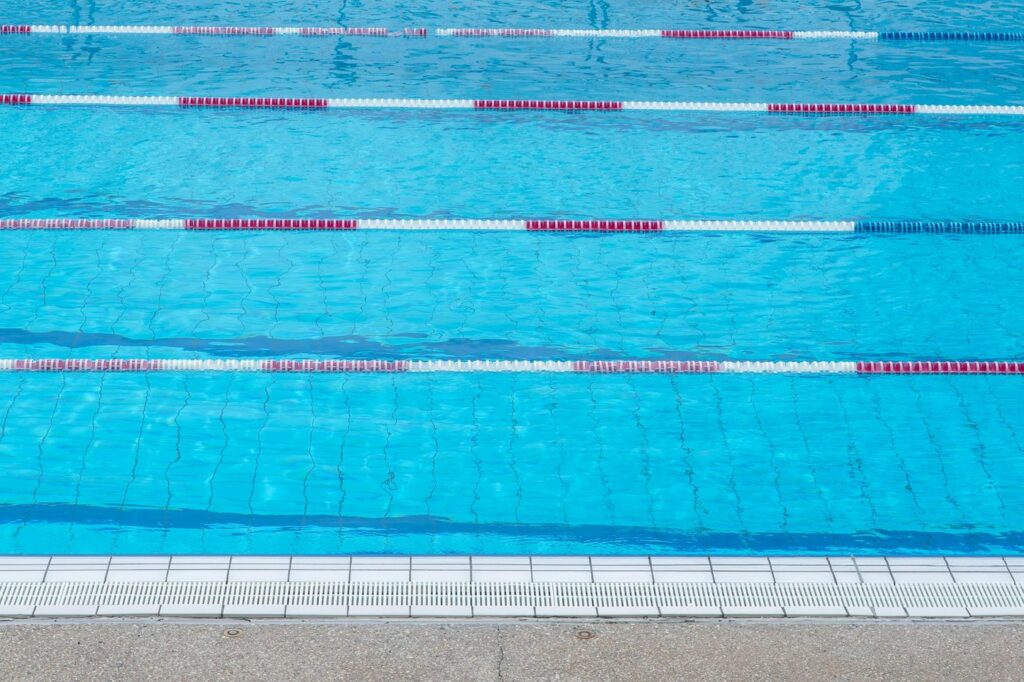 Clear blue water in an outdoor swimming pool with marked swim lanes.
