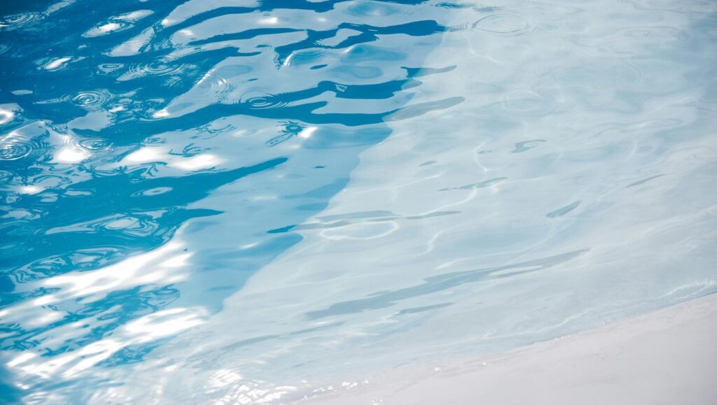 Glistening blue pool water with sunlit ripples creating a serene and refreshing