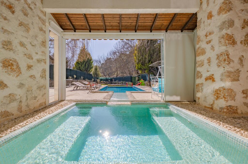 Sophisticated view of a mansion with pools and stone patio, ideal for luxury ret