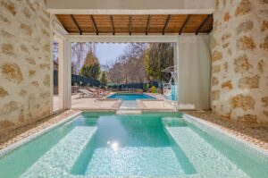 Sophisticated view of a mansion with pools and stone patio, ideal for luxury ret