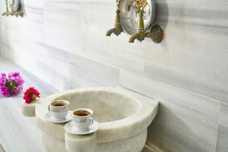 Turkish coffee cups elegantly placed on a marble sink with ornate faucets, evoki